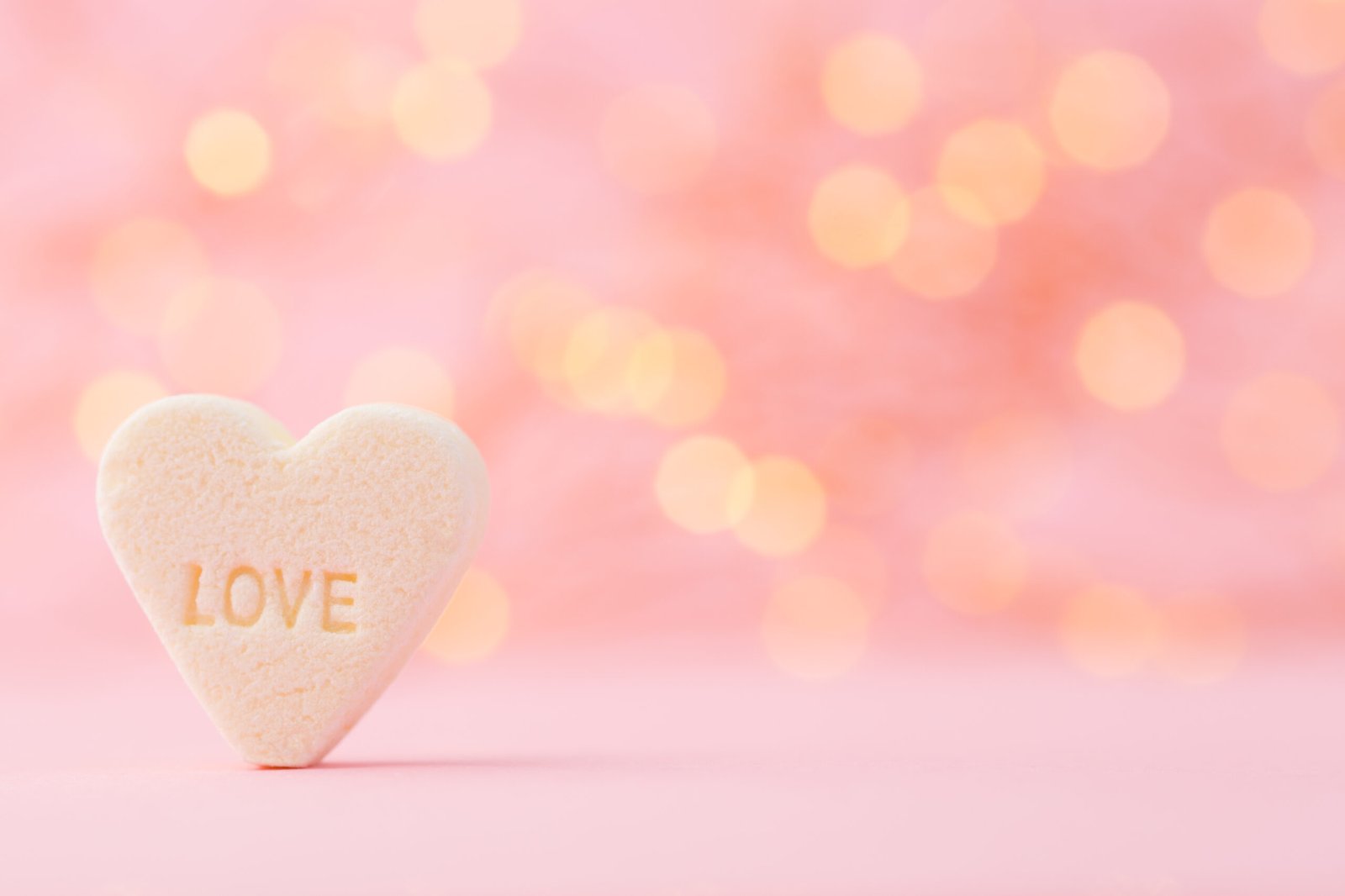 Pastel colored candy hearts in a bokeh background - Sugarspoon Desserts
